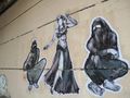 جرافيتي لمرأتان جالستان وترتديان النقاب وامرأة ترقص وهي ترتدي بدلة رقص.jpg